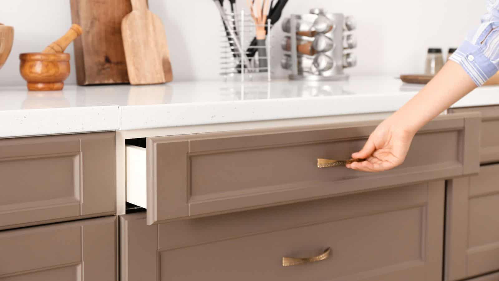 woman opening kitchen drawer, brass handles