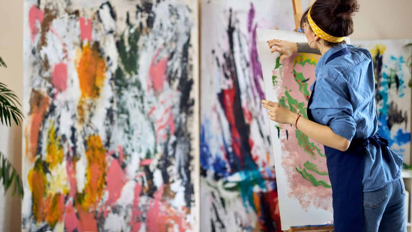 back of an inspired talented woman, female artist painting at home studio