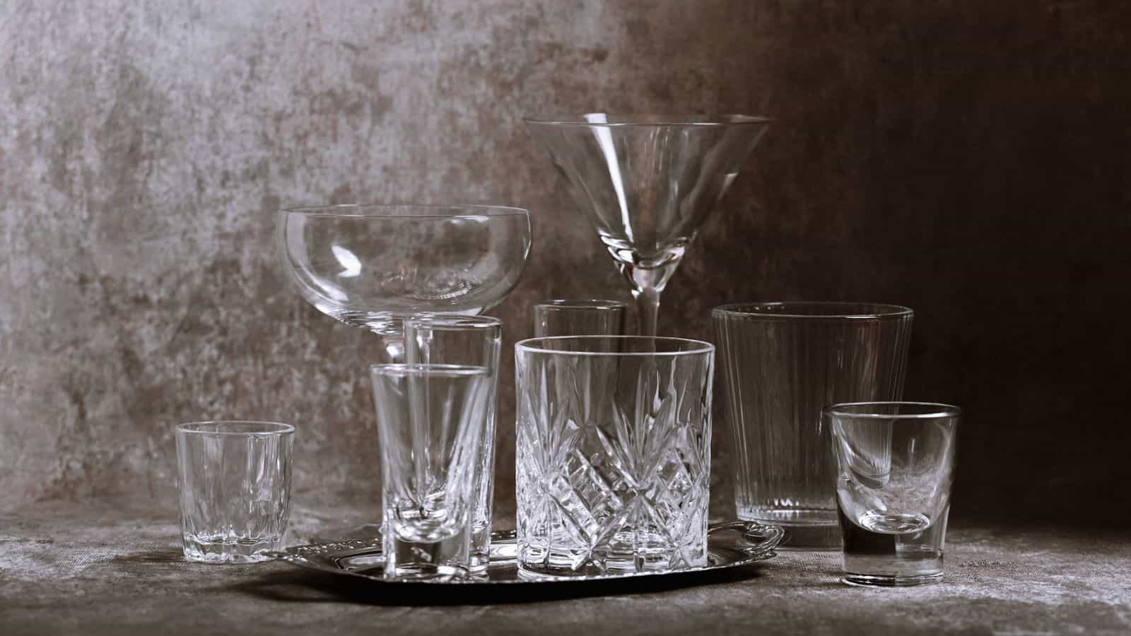 Collection of empty crystal glasses of varying sizes and shapes arranged elegantly on a textured tabletop