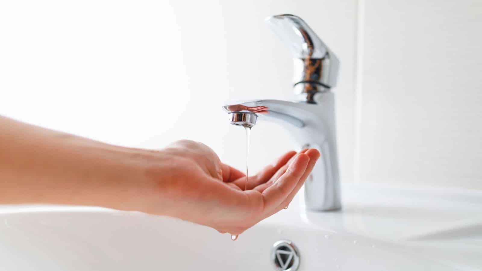 Hand under faucet with low pressure water stream