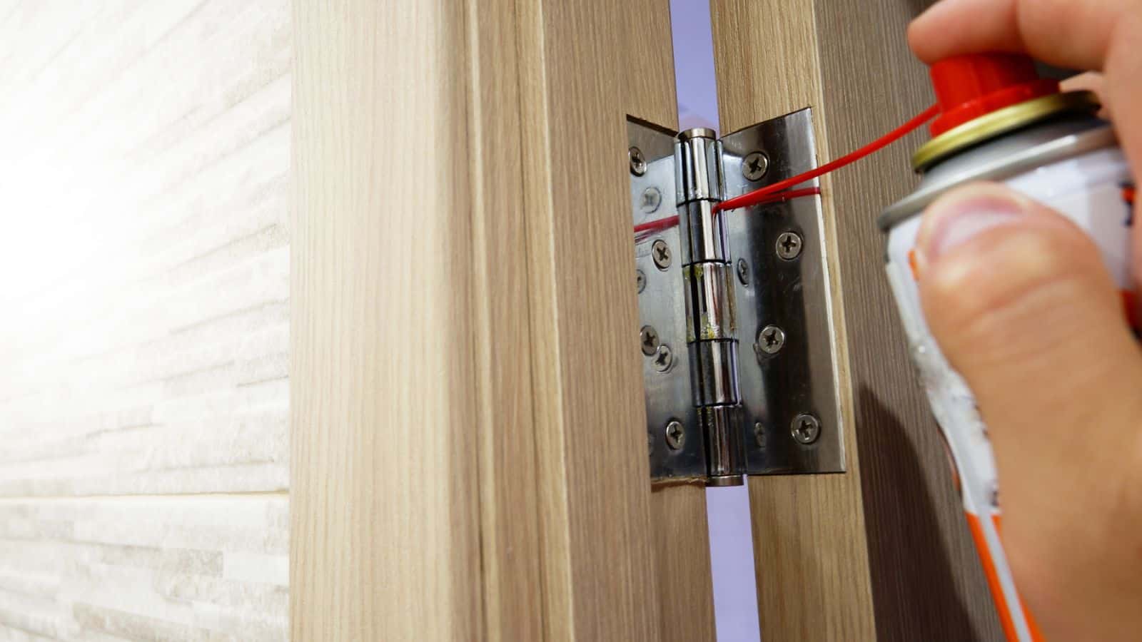 A man lubricates door hinges with oil