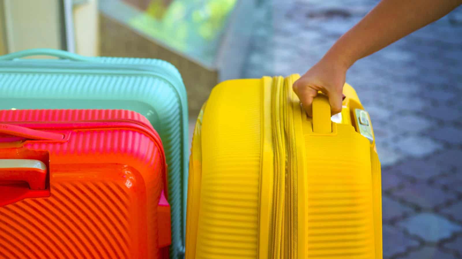Hand holds the handle of a colorful luggage