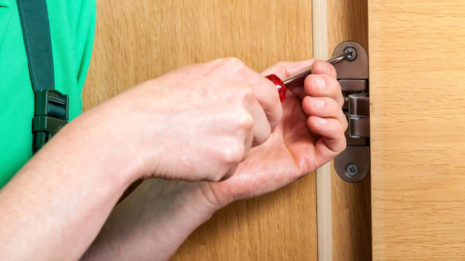 Hands repairing a door hinges